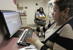 In this Sept. 5, 2013 photo, Jacqueline Saulsberry, a service coordinator at the Illinois Eye Institute, gathers information from patient Shameka Lewis-Coolidge during an appointment in Chicago. [CREDIT: M. Spencer Green, for The Associated Press]
