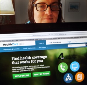 In a photo taken Monday Oct. 28, 2013, in Portsmouth, N.H., Deborah Lielasus poses behind her computer with the national health insurance enrollment website. [CREDIT: Jim Cole, for The Associated Press]