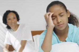 Nurse watching girl (7-9) with migraine in hospital